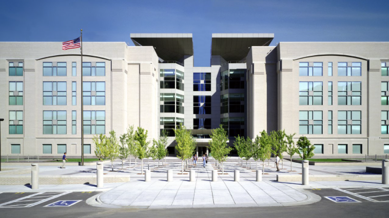 A four-story light colored building with many windows on the front.